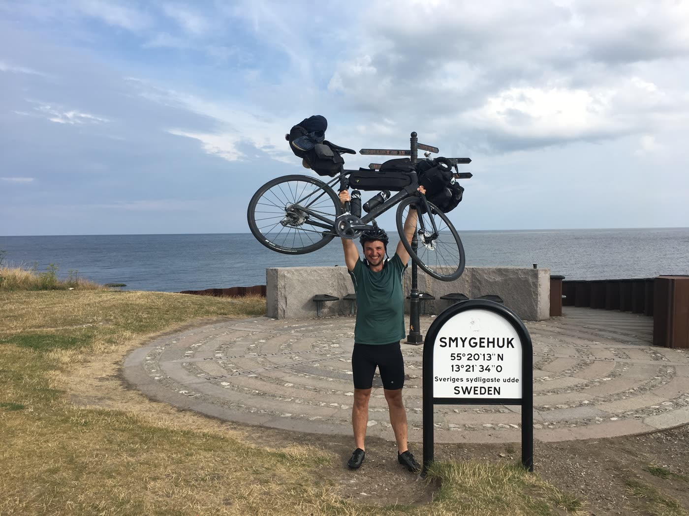 Holding the bicycle overhead at Smygehuk, the southernmost point of Sweden
